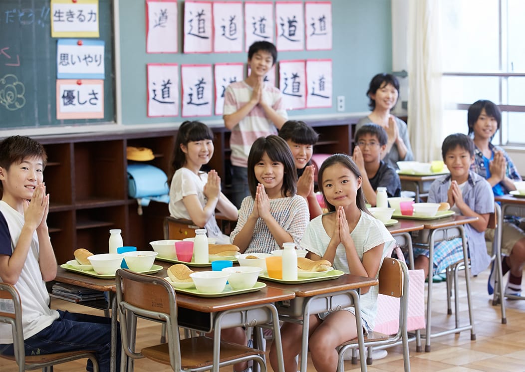 学校給食の前で手を合わせている小学生たちの写真